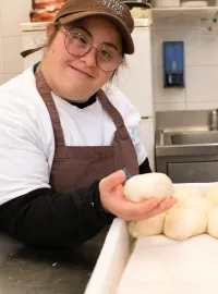 Una ragazza con grembiule e cappellino prepara i panetti per le piadine