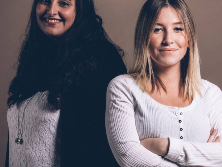 Due giovani donne a braccia conserte sorridono.
